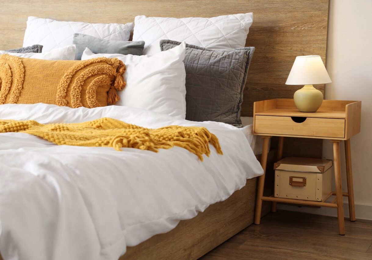 Interior of stylish bedroom with cozy bed and lamp on bedside table