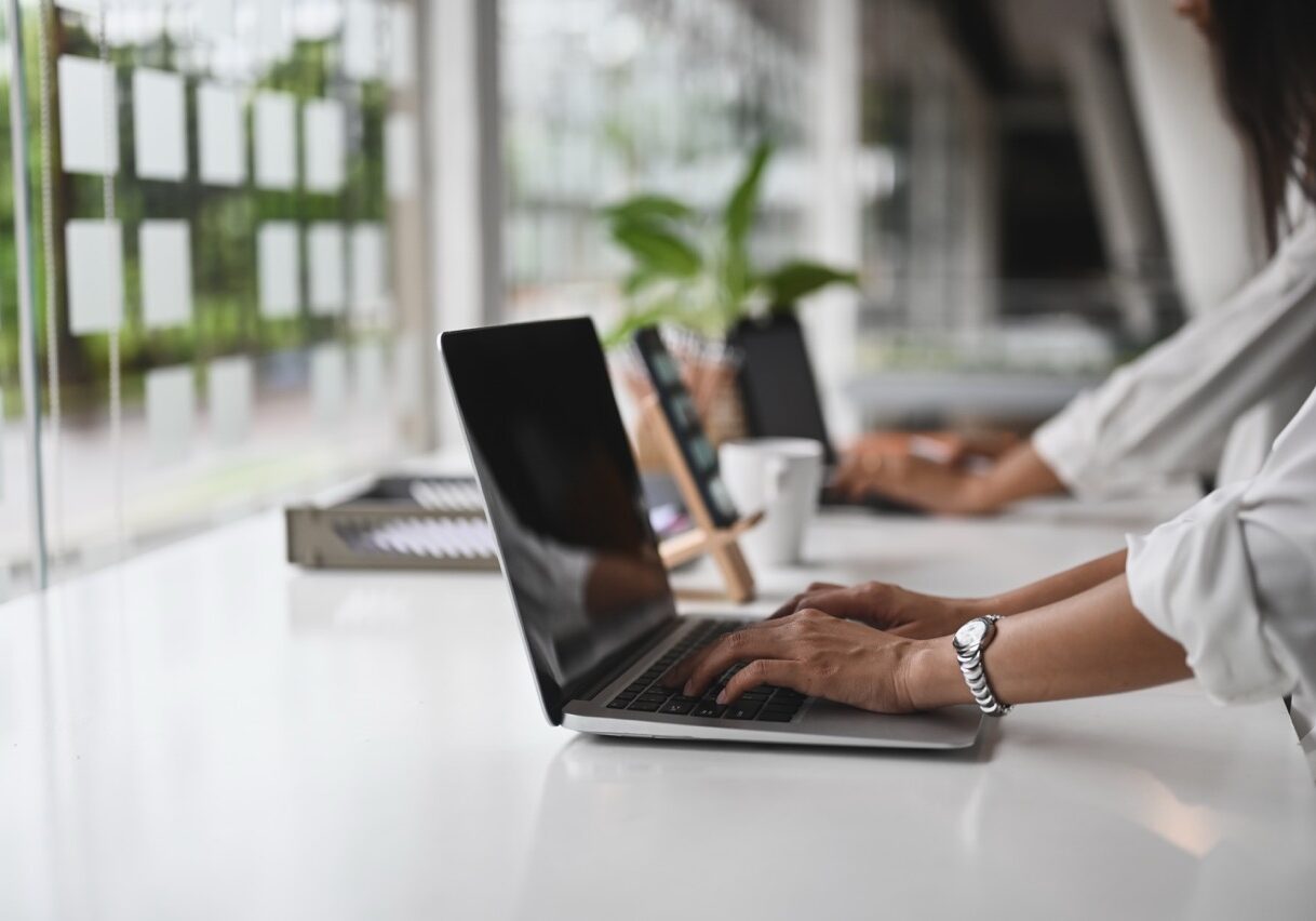 Cropped image of office women's hands is using a computer laptop on the counter.